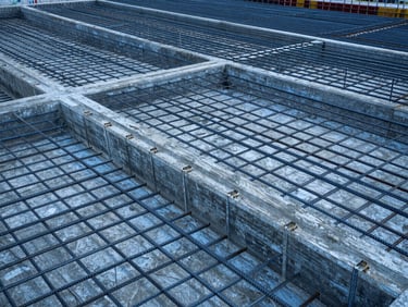 Orthographic high-resolution view of a reinforced concrete foundation with detailed steel rebar grids, cool blue and slate tones, overcast daylight, sharp structural geometry, 35mm