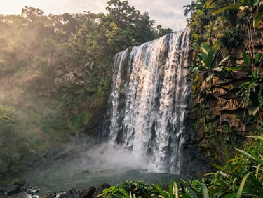 Majestic Tumpak Sewu waterfall surrounded by lush tropical jungle, soft morning mist, cinematic composition