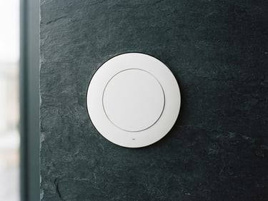 Sleek white circular access point mounted on a dark slate wall, clean architectural lighting, sharp focus, technical minimalism, 35mm