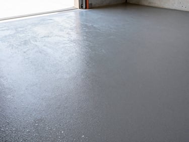 Close-up of a freshly cured gray epoxy flake garage floor, high-contrast clean texture, bright natural daylight streaming from an open garage door, sharp focus