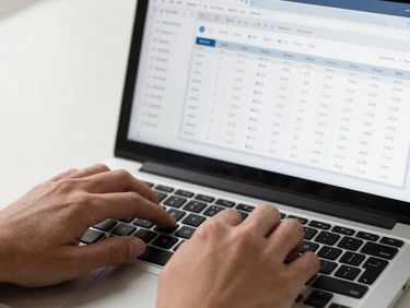 Extreme close-up overhead view of hands typing on a laptop keyboard, browser window visible on screen showing an SEO audit dashboard with keyword ranking columns, clean studio light from left, high contrast, no faces