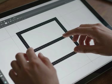 Extreme close-up of hands positioning layout frames in a browser-based design tool, clean overhead studio light, grid lines visible on screen, cool neutral surface