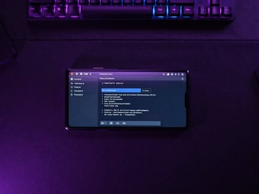 Top-down flat lay of a clean developer workspace with an Android test device showing a terminal output, moody violet rim lights, 85mm