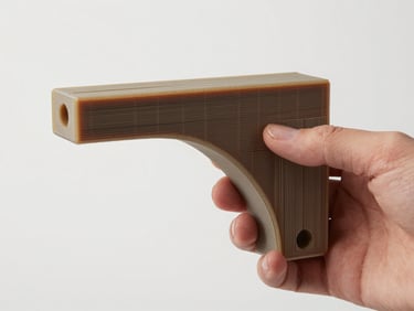 Side-profile close-up of a complex 3D-printed resin structural bracket held in a bare hand against a neutral white studio background, even diffused light revealing surface finish and layer cross-section, no glare