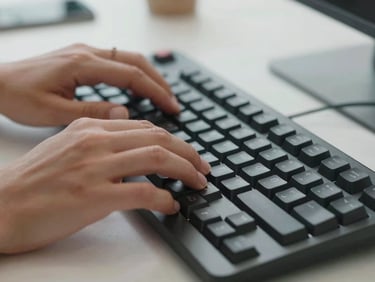 Tight macro shot of professional hands typing on a sleek mechanical keyboard in a clean, minimalist Australian office space.