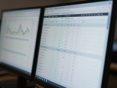 Close-up macro shot of a dual-monitor setup displaying stylized, blurred financial spreadsheets and servicing calculators, cool professional lighting.