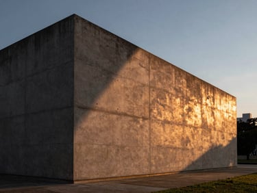 Cinematic medium shot of a brutalist concrete pavilion in São Paulo at dusk. A dramatic diagonal shadow cuts across the raw concrete wall, illuminated by warm copper and amber lighting from an unseen source, creating a high-contrast architectural vignette.