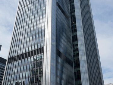Sleek, modern skyscraper in Frankfurt's financial district, reflecting the sky, clean architectural lines, professional corporate photography, cool natural daylight.