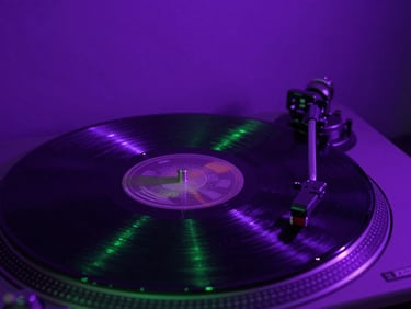 Macro shot of a vinyl record spinning on a turntable under moody electric violet strobes.