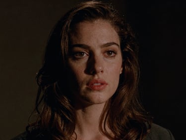 Cinematic film still, high-contrast portrait of a woman in low-key lighting, rich color-graded shadows, anamorphic lens, 35mm grain