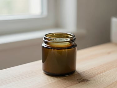 Amber glass jar of herbal balm sitting on a light wooden surface in a clean, airy bathroom, soft diffused natural daylight.