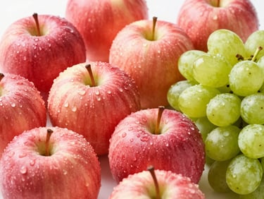 Close-up, vibrant shot of organic red apples and green grapes with water droplets, bright natural daylight, crisp focus.