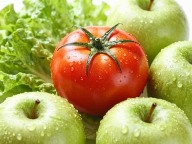 Vibrant close-up of a perfectly ripe tomato, crisp lettuce, and shiny green apples, with water droplets, bright natural morning light, high-key depth of field.