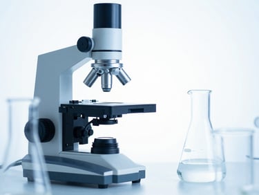 High-key studio shot of precision laboratory scientific equipment and glass labware, sterile white background, cool blue lighting