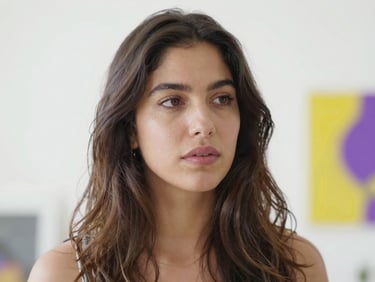 Soft-focus portrait of Elena Vega, the artist, looking contemplative in her studio, bathed in natural light, ethereal, high-key white backdrop, 50mm.