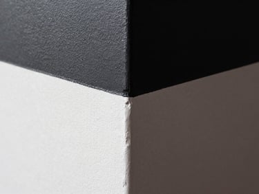 Extreme close-up of a perfectly painted wall corner, razor-sharp paint line transition from deep charcoal to stark white, dramatic raking light highlighting smooth micro-texture, 35mm lens