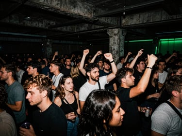 Wide-angle crowd scene at an underground warehouse party, high-contrast flash lighting, deep shadows, electric neon green accents, raw festival energy.