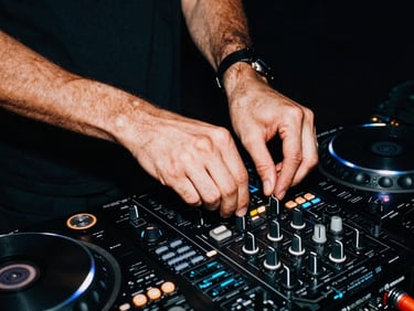 Gritty close-up action shot of DJ hands adjusting mixer knobs on a dark deck, high-contrast flash, saturated cyan ambient light, deep shadows.