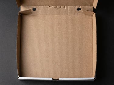 Direct overhead studio flatlay of a single open-top corrugated pizza box, white exterior with clean die-cut edges, side-lit to reveal board thickness and fluting texture, no food, no props