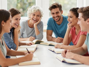A group of multi-generational students sharing a laugh around a table with Italian books, bright daylight, authentic expressions.