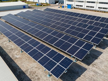 Vista aérea de uma grande instalação de painéis solares industriais sobre o telhado de uma fábrica moderna, sob luz solar clara do dia, linhas geométricas limpas.