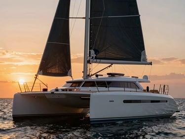 Luxury catamaran with spacious open-concept trampoline deck, sailing towards the sunset, warm orange light.