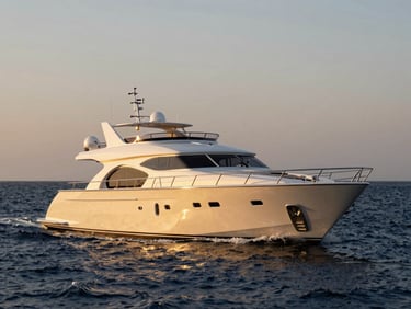Classic luxury yacht cutting through deep blue water, low-sun golden hour illuminating the sleek hull.