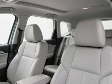 Interior close-up of a clean, premium car cabin with leather seats, soft natural light filtering through the window, showing a tidy and professional setup.