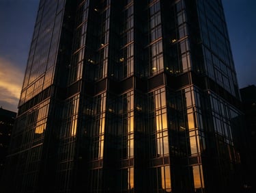 Sleek modern skyscraper facade of steel and glass, sharp dramatic low-key lighting, golden hour reflections on dark metal, 35mm