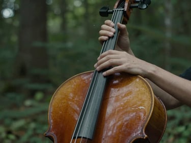 Close-up of hands gently touching the strings of a wooden cello, soft moody lighting, forest green background