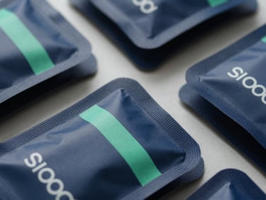 Macro overhead shot of high-end consumer product packaging ready for shipping, sharp shadows, cool natural daylight, deep navy tones