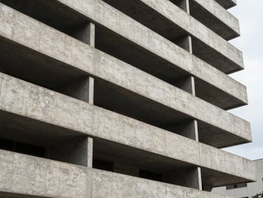 Close-up architectural detail of a finished reinforced concrete facade on a mid-rise residential building in São Paulo, sharp shadow lines from window reveals cutting across the concrete plane, overcast diffused natural light, no people, strong horizontal geometry