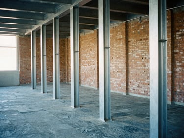Industrial interior renovation with exposed brick and newly installed steel support columns, cool-toned 35mm film photography