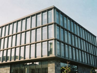 Exterior facade of a modern steel and glass commercial building under crisp morning daylight, sharp focus