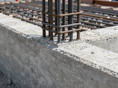 Close-up of freshly poured concrete joint with steel reinforcement bars visible on an active commercial loading dock rehabilitation site, crisp daylight.