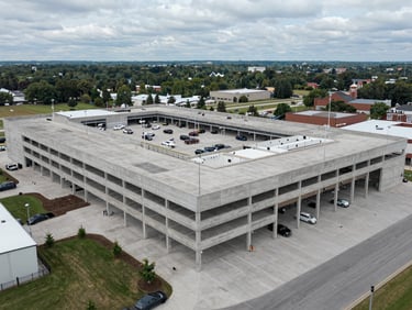 Wide-angle drone shot of a massive completed retail plaza concrete parking deck and structural loading dock in Vaughan, overcast daylight