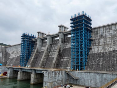 Wide-angle shot of a hydroelectric dam under construction in Malaysia, cool overcast daylight, structural steel blue tones, sharp technical detail.