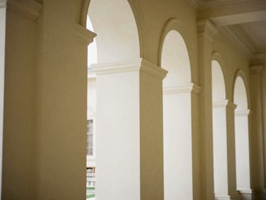Architectural detail of classical library columns and high arched windows, minimalist composition, warm tones, warm editorial photography, 35mm