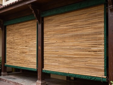 An elegant hotel courtyard verandah in Lucknow featuring large-scale, heavy-duty bamboo blinds with dark green fabric borders.