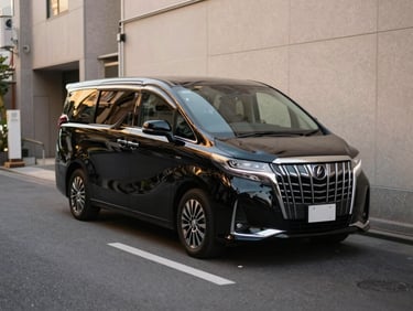 Polished luxury black executive van parked quietly in a narrow, clean Tokyo side street, subtle golden hour reflection