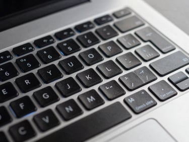 Macro shot of clean modern laptop keyboard with subtle electric blue backlighting, technical precision, high contrast