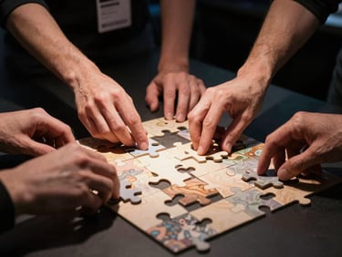 Close-up of four pairs of hands actively solving a large-format puzzle on a dark table at an indoor event, concentrated focus, warm studio spotlight illuminating the puzzle pieces and hands, dark dramatic background