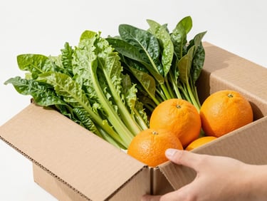 Crisp close-up of a hand opening a clean cardboard box to reveal vibrant organic greens and orange citrus fruits, bright high-key studio lighting, 50mm lens