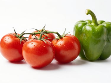 Fresh organic vine tomatoes and bell peppers, bright daylight, clean white background