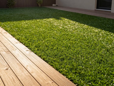 Crisp deck lines meeting perfectly laid artificial turf in a modern backyard, bright natural golden-hour sunlight.