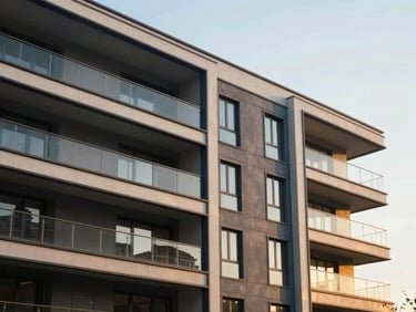 Elegant medium-wide architectural shot of a modern residential building facade under warm golden-hour daylight, clean lines, deep navy shadows, 35mm photography.