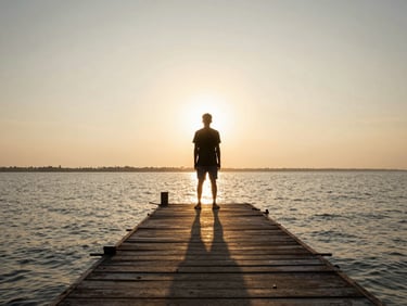 Cinematic wide shot of a solitary figure standing on a Kerala backwater pier at golden hour, dramatic long shadows, 2.39:1 aspect ratio.