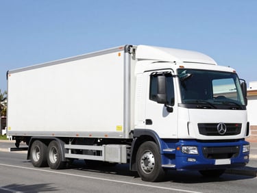 Wide shot of a clean white and blue commercial transport truck parked on an Alicante street under bright Spanish daylight, hydraulic tail lift lowered, crisp commercial photography, 35mm lens