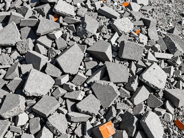Close-up of grey crushed recycled concrete aggregates, sharp edges, industrial texture, bright daylight