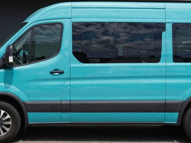 Side profile of a matte black commercial van being wrapped with a high-contrast cyan vinyl graphic, clean installation process.